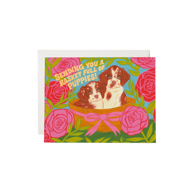 Illustration of a basket of puppies with flowers in the background and text that reads "sending you a basket full of puppies" 
