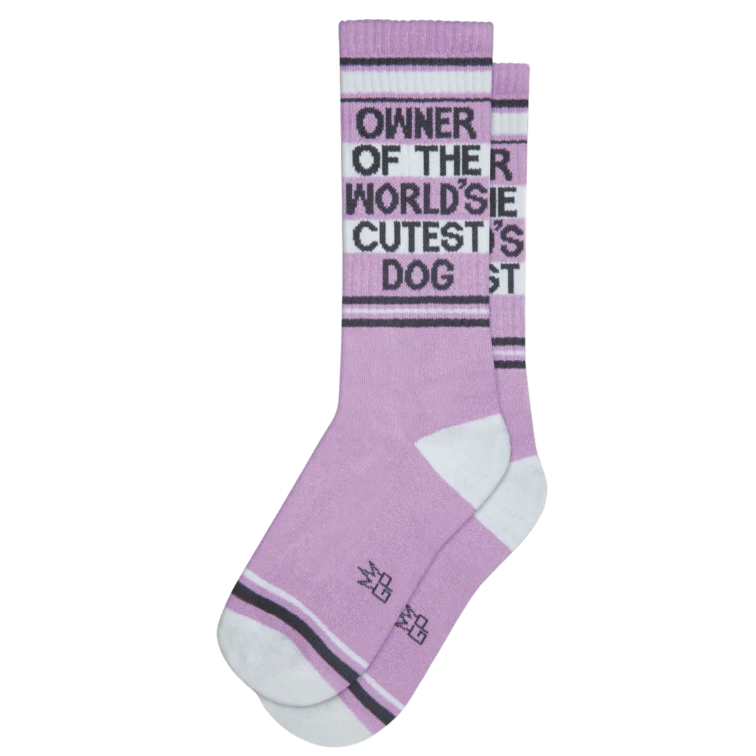 Purple sock with white and grey stripes and text "Owner Of The World's Cutest Dog". Journey to comfort and style with these one-size, USA-crafted socks - welcoming coziness and zesty design with every step. Your pup may be cute, but these socks make life more livable! 🐶