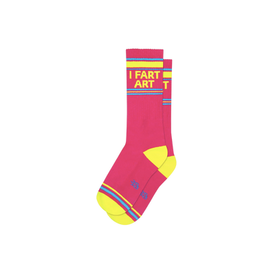 Pink socks with blue and yellow stripes and text "I Fart Art". Art can take on many shapes. You can listen to it 🎶, witness it 🎭, taste it 👨‍🍳, feel it 🤡, or smell it 👃. With I Fart Art Gym Socks, you get it all! 💨 Capture the essence of your individuality and give it a name 🖼 Crafted in the United States, using 62% Cotton, 32% Nylon, and 3% Spandex.